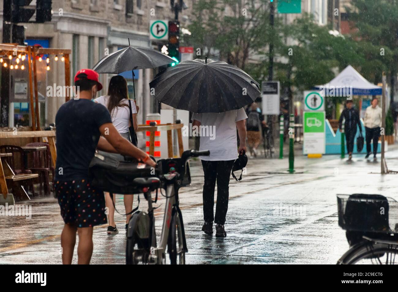 Montréal, CA - 30 juillet 2020 : personnes sur l'avenue Mont-Royal tenant des parasols sous la pluie et la tempête Banque D'Images