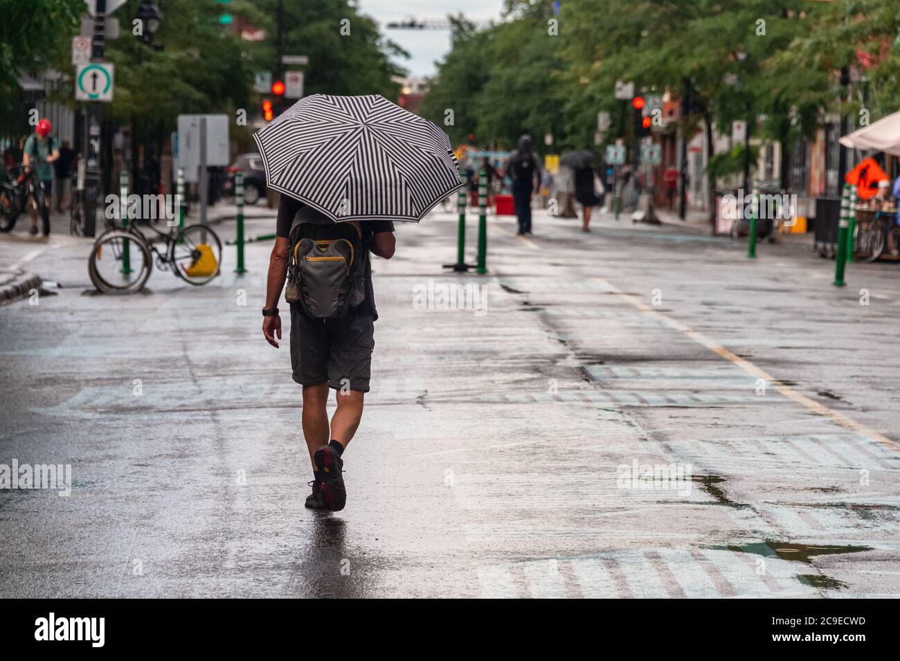 Montréal, CA - 30 juillet 2020 : un homme sur l'avenue Mont-Royal tenant un parapluie sous la pluie et la tempête Banque D'Images