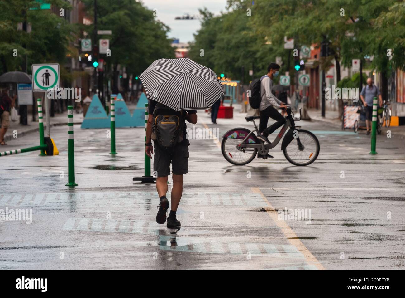 Montréal, CA - 30 juillet 2020 : un homme sur l'avenue Mont-Royal tenant un parapluie sous la pluie et la tempête Banque D'Images