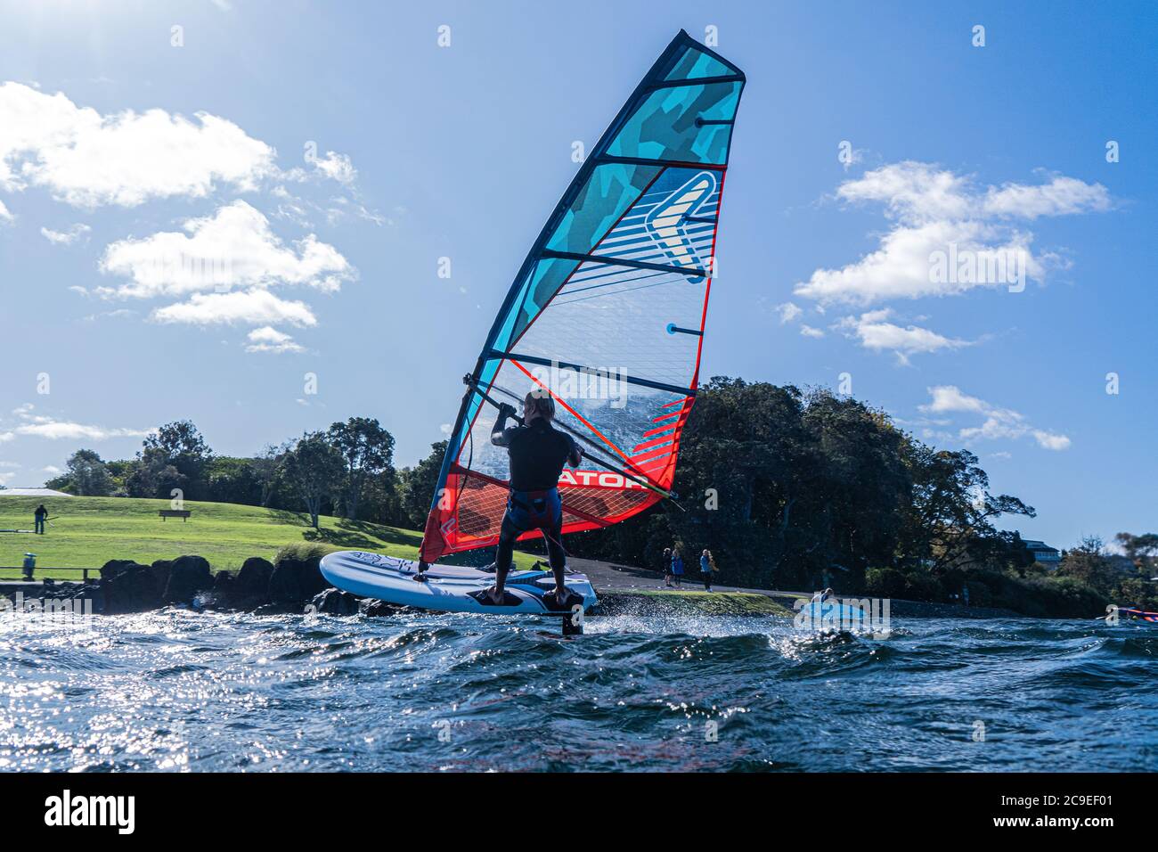 Un jeune homme en combinaison navigue sur un lac une planche à voile  hydrofoil. Fond bleu ciel Photo Stock - Alamy
