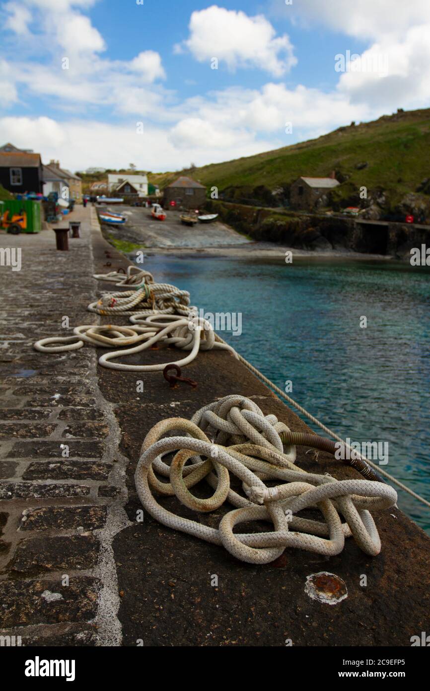Gros plan de cordes d'amarrage enchevêtrées liées à des anneaux métalliques sur un quai en pierre. Ces cordes de navire sont utilisées pour attacher des bateaux au quai dans ce petit poisson Banque D'Images