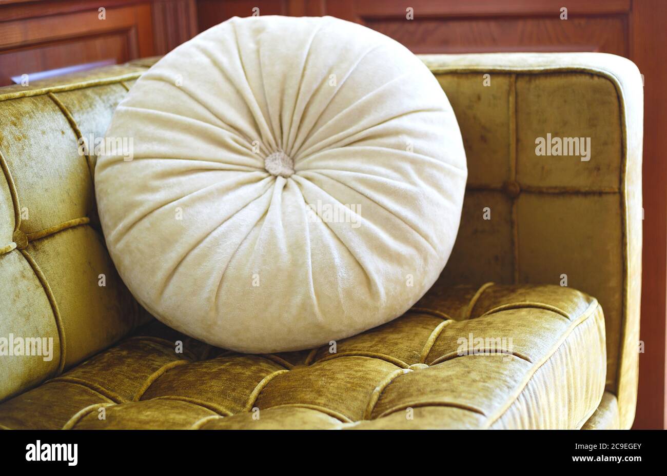 coussin rond beige sur un canapé en velours doré Photo Stock - Alamy