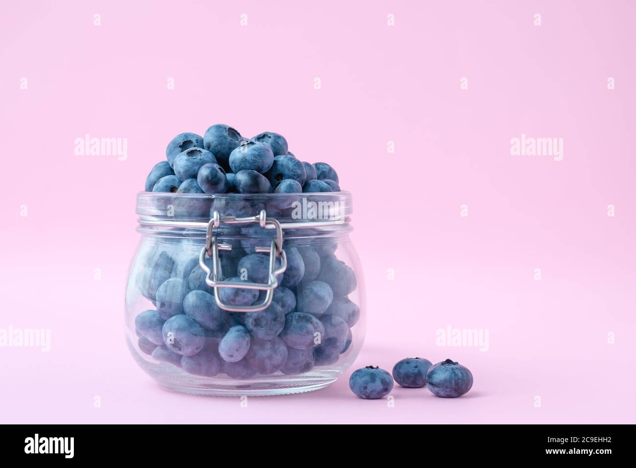 Bleuets dans un bol en verre sur fond rose, baies dans un pot en verre. Concept de cuisine végétarienne Banque D'Images