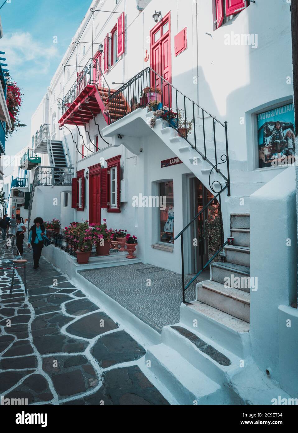 Maisons colorées et commerce aux couleurs bleu et blanc avec des fleurs dans la vieille ville de l'île de Mykonos, Grèce. Banque D'Images