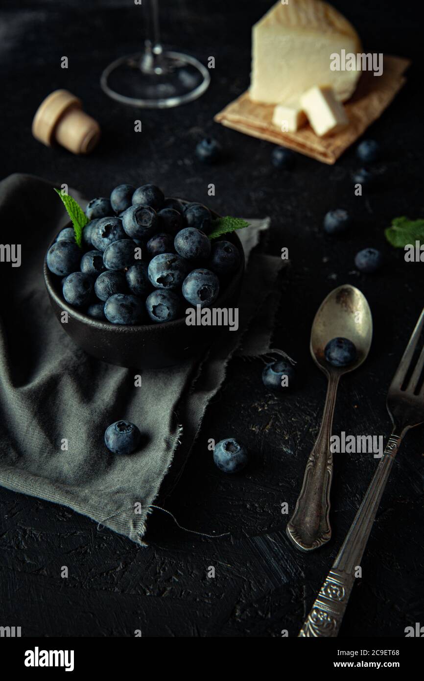 Bleuets frais, vin rouge et fromage maison, sur la table en bois sombre. Banque D'Images
