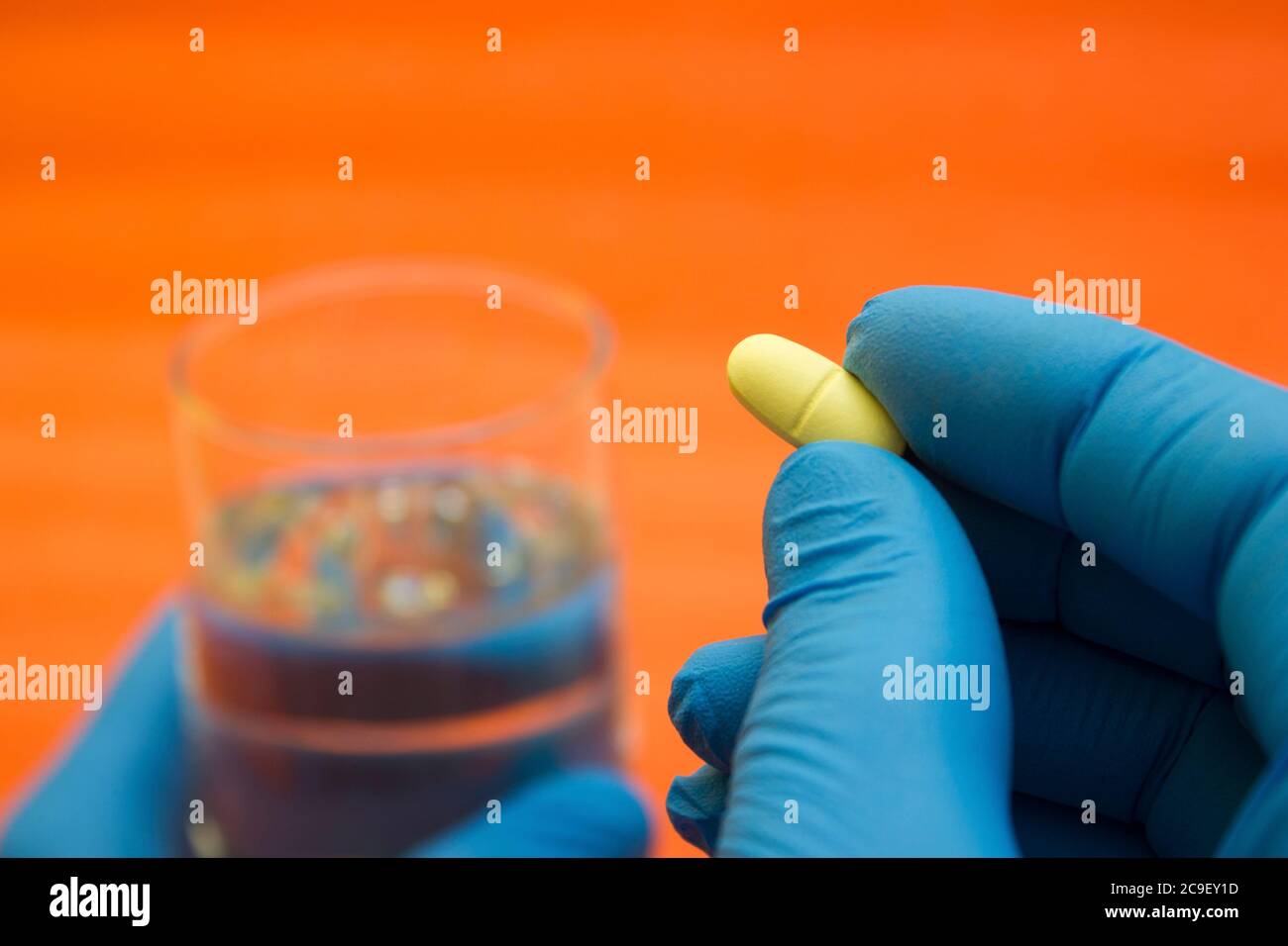 Mains dans les gants médicaux prendre une pilule avec un verre d'eau - choix de la médecine, les médecins sont malades, coronavirus, covid19 Banque D'Images