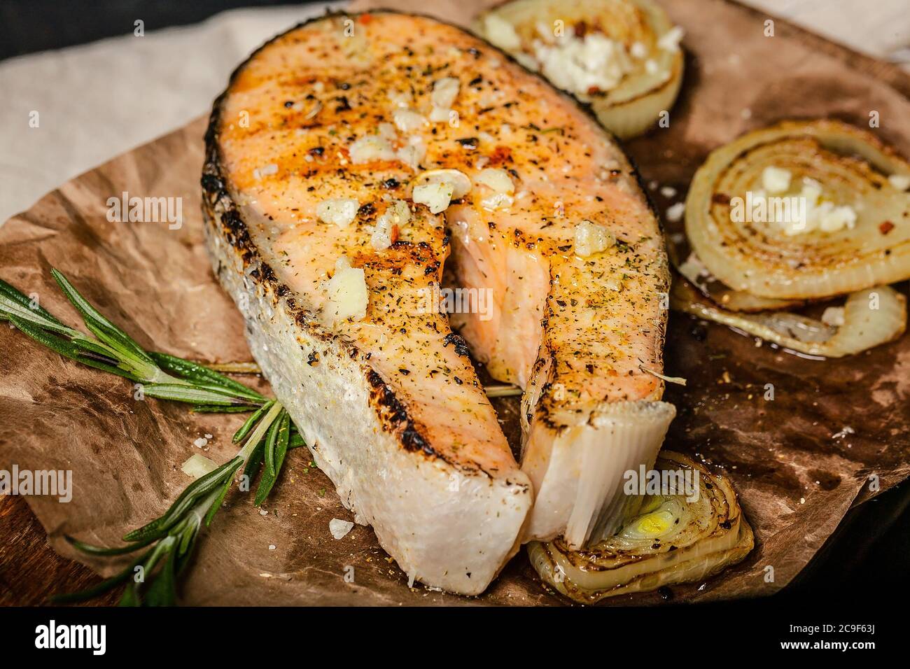 Steak de saumon grillé à l'ail, à l'oignon et aux herbes sur une planche à découper en bois. Gros plan Banque D'Images
