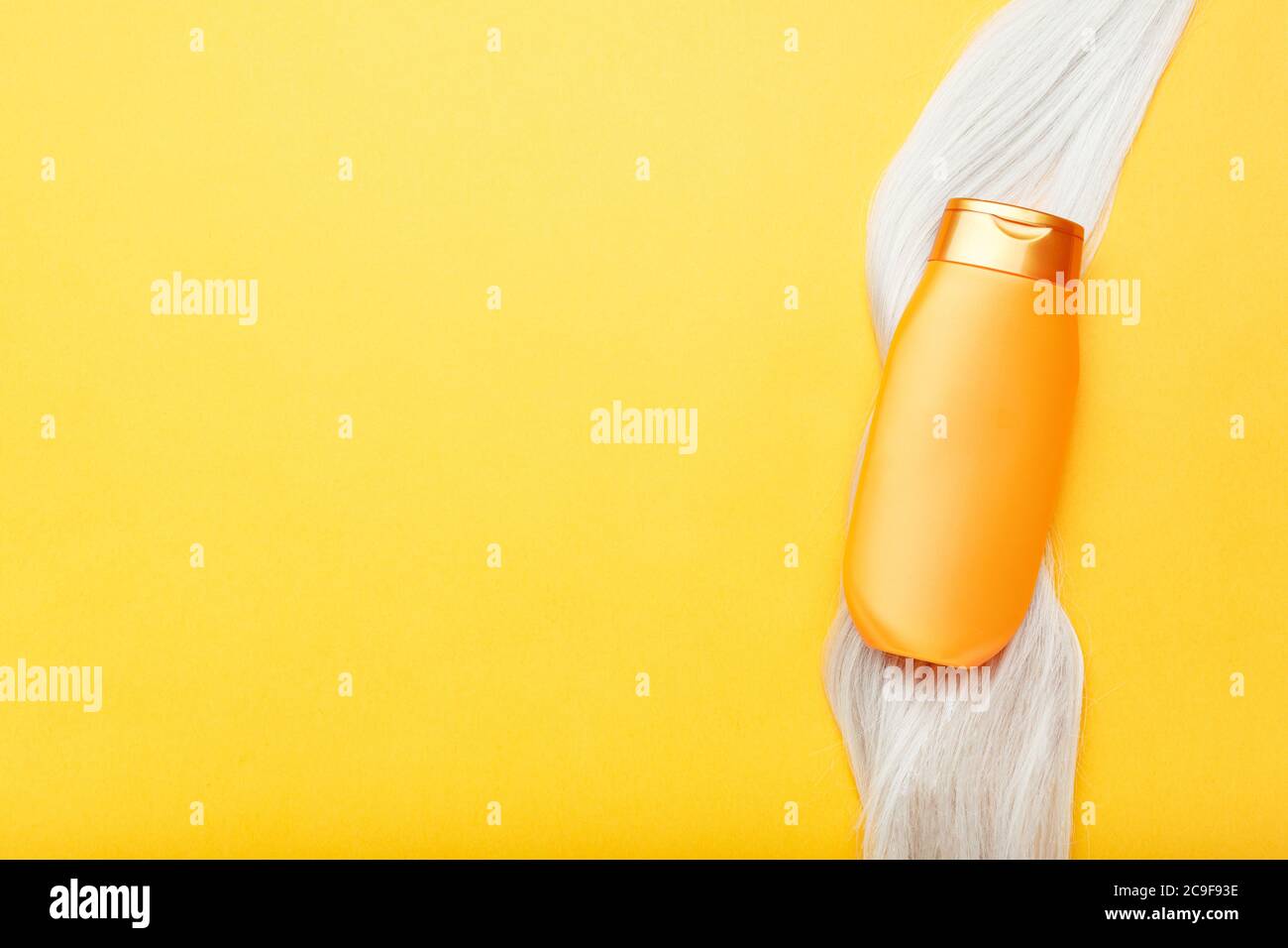 Bouteille de shampooing maquette sur une serrure de cheveux blonds sur fond de couleur orange. Shampoing doré en fil de cheveux teint. Soins des cheveux cosmétiques bain beauté Banque D'Images