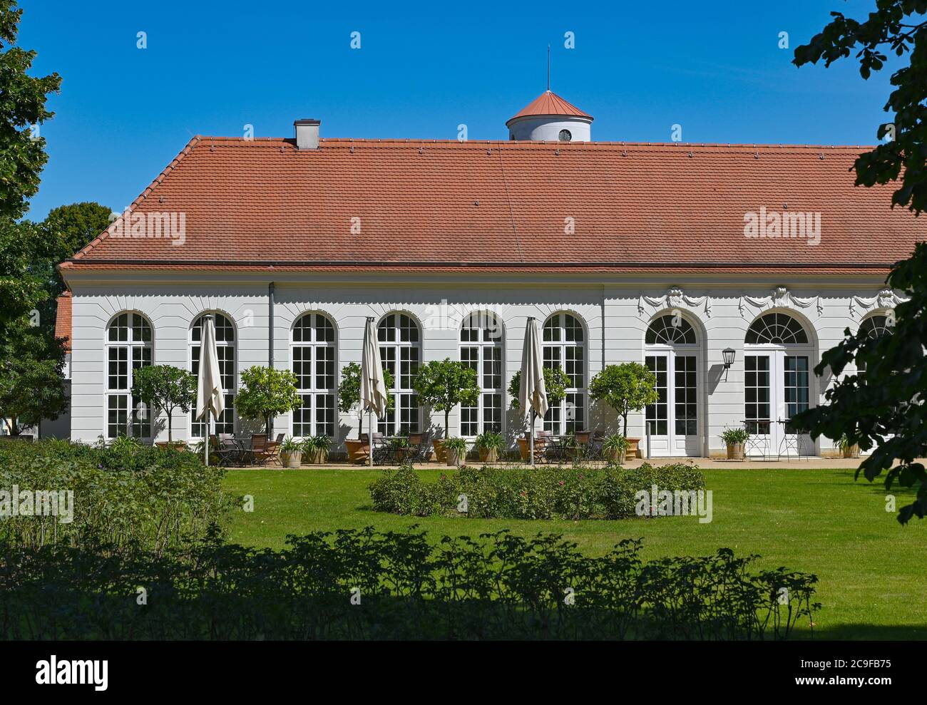 Neuhardenberg, Allemagne. 31 juillet 2020. Le bâtiment de l'Orangerie dans le jardin de la Fondation Schloss Neuhardenberg. En arrière-plan, la tour de l'église de Schinkel s'élève dans le ciel bleu. Après la pause liée à une pandémie, le Stiftung Schloss Neuhardenberg se déplace à l'extérieur avec un nouveau programme d'été à partir du 1er août 2020. Jusqu'en 23.08.2020, environ 20 événements dans le parc du château sont sur le programme. Credit: Patrick Pleul/dpa-Zentralbild/ZB/dpa/Alay Live News Banque D'Images