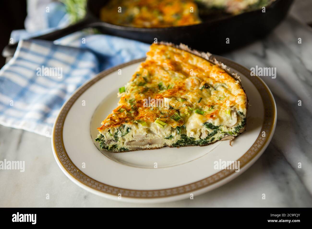 Frittata maison fraîche cuite dans une casserole en fonte avec découpe en tranches sur une assiette Banque D'Images