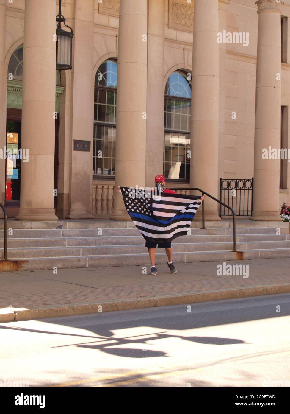 Oneonta, NY / USA - 31 juillet 2020 : un manifestant à l'hôtel de ville fait défiler un drapeau de ligne bleue en opposition à un monument commémoratif BLM approuvé par la ville Banque D'Images