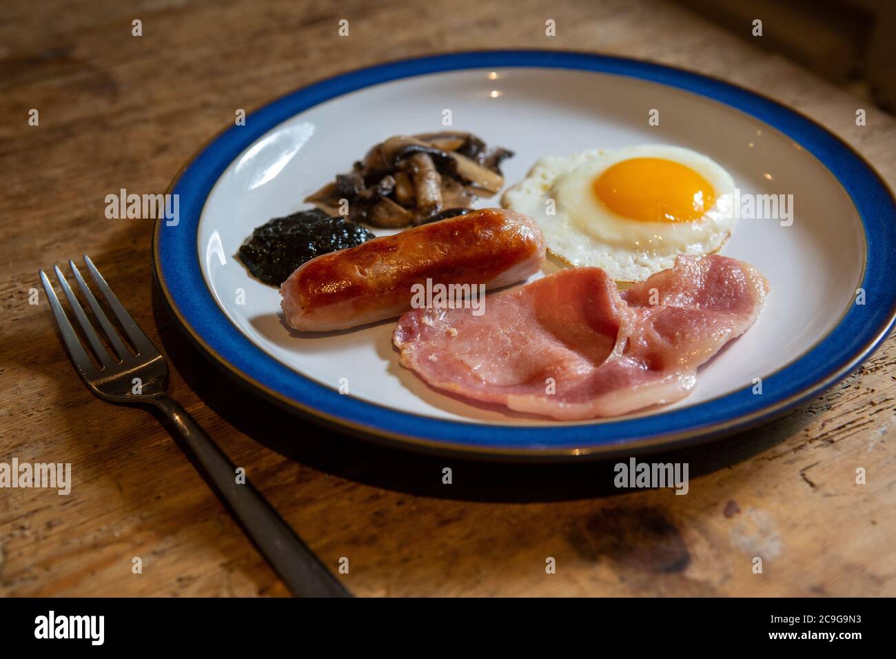 Assiette avec petit déjeuner cuisiné gallois complet composé d'œufs, saucisse, bacon, champignons et pain de lave Banque D'Images