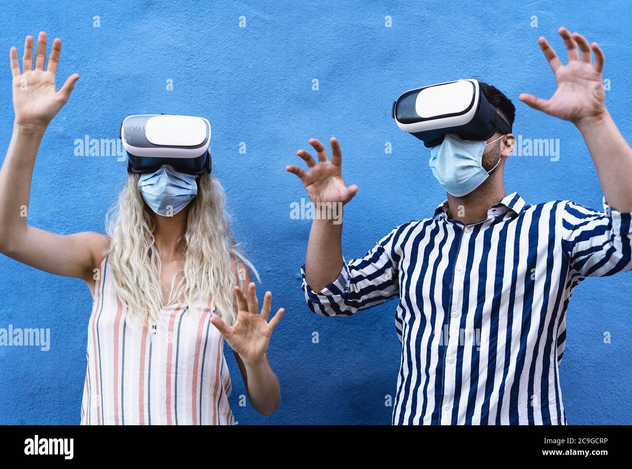 Jeune couple portant un masque chirurgical de visage s'amusant avec des lunettes de réalité virtuelle pendant l'épidémie - les personnes du millénaire utilisant la vr innovante Banque D'Images