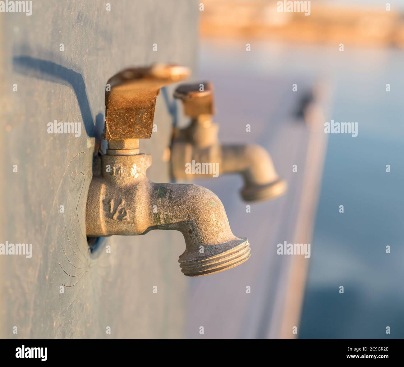 robinet d'eau extérieur en gros plan avec écoulement d'eau calcifiée souillée au calcaire. robinets en laiton avec dépôts de chaux et un peu de rouille Banque D'Images