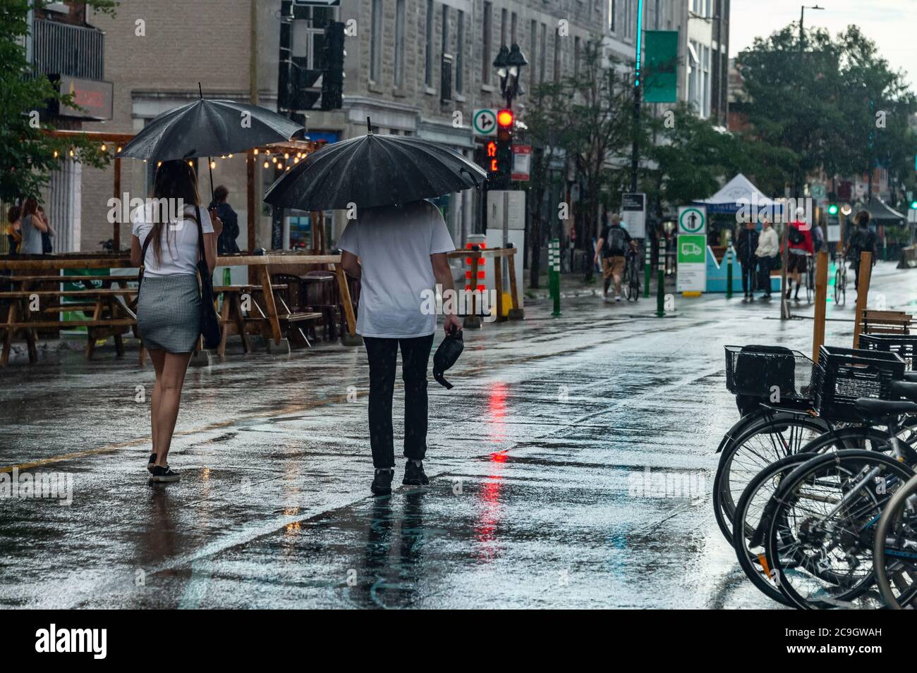 Montréal, CA - 30 juillet 2020 : personnes sur l'avenue Mont-Royal tenant des parasols sous la pluie et la tempête Banque D'Images