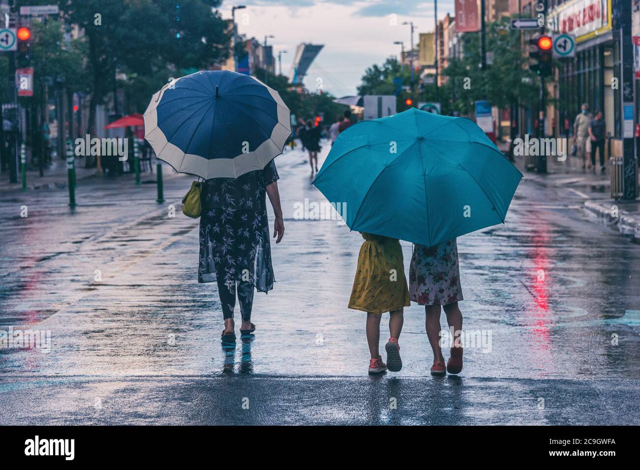 Montréal, CA - 30 juillet 2020 : mère et fille sur l'avenue Mont-Royal tenant des parasols sous la pluie et la tempête Banque D'Images