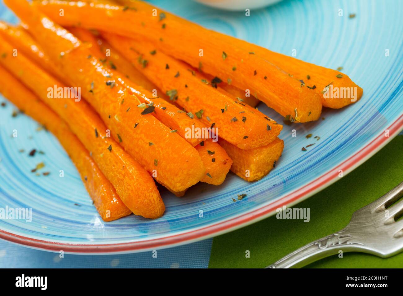 Délicieux bâtonnets de carottes cuits servis avec de la crème fraîche rustique et des légumes verts Banque D'Images