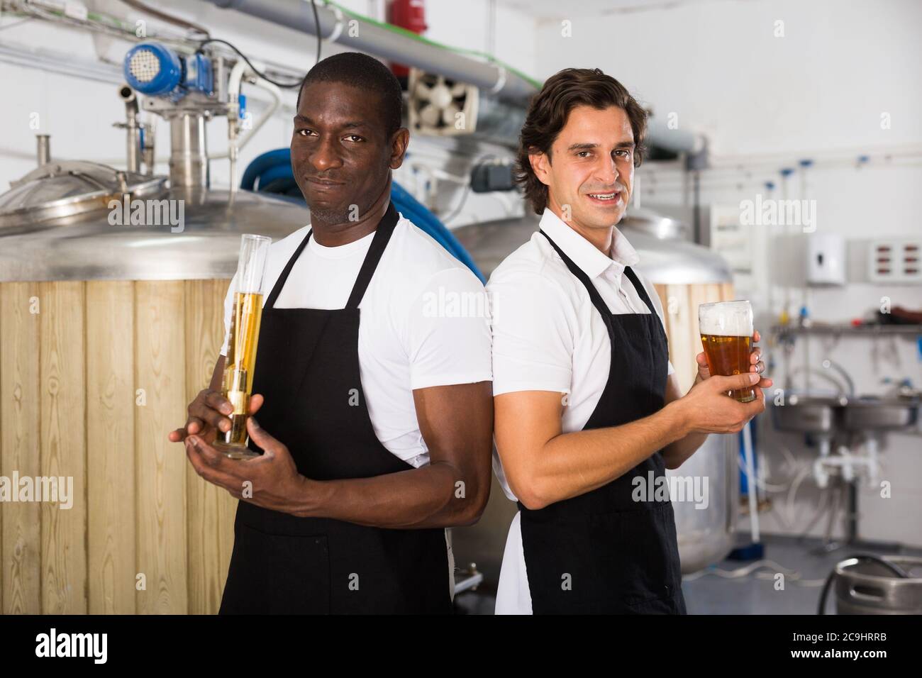 Deux brasseurs professionnels montrant le verre et la fiole de bière en usine brasseur Banque D'Images