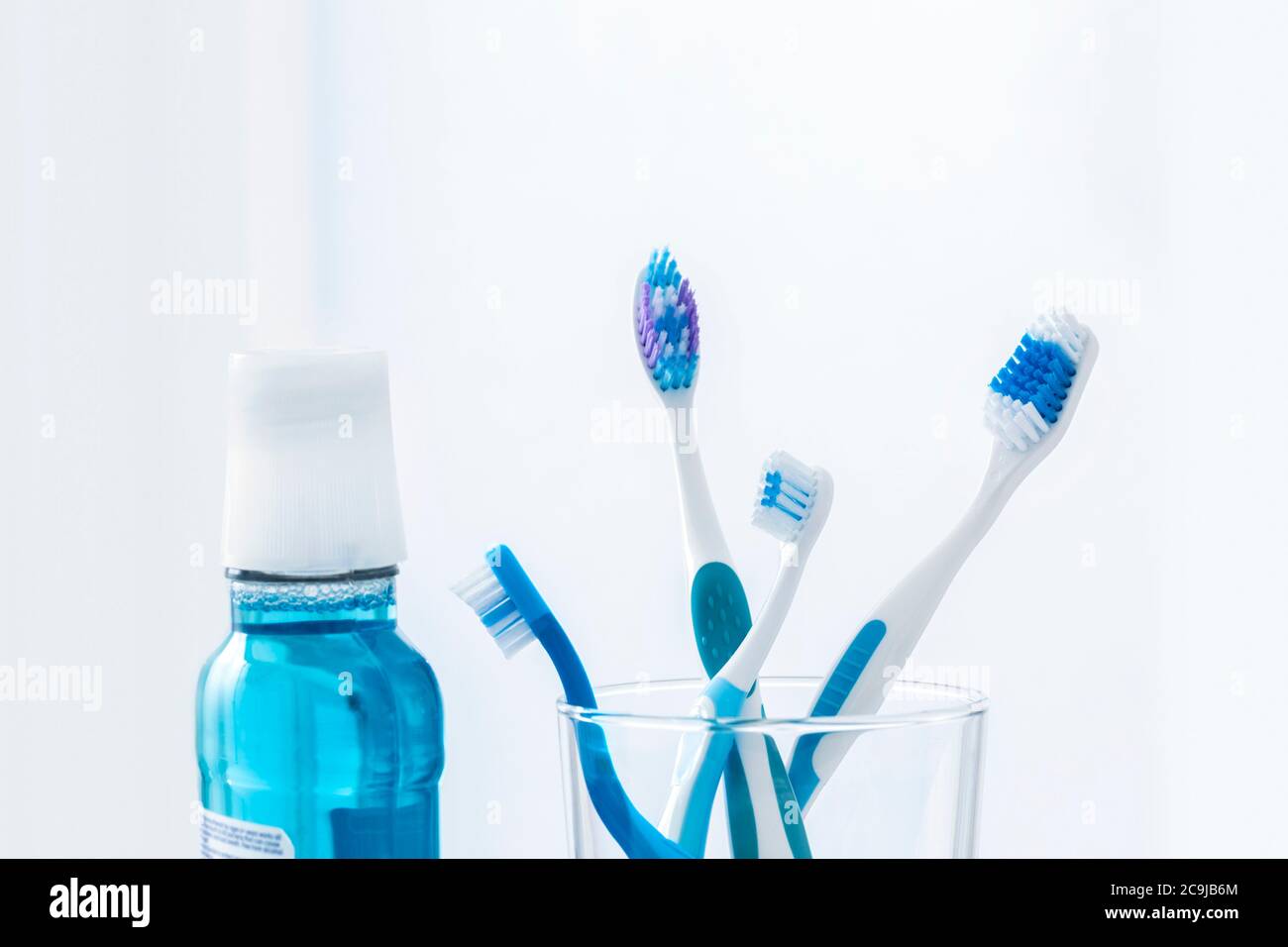 Brosses à dents en verre avec bain de bouche sur fond simple. Banque D'Images