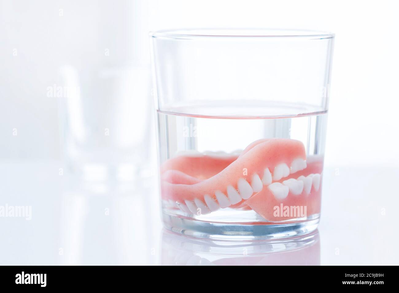 Dentiers dans un verre d'eau. Banque D'Images