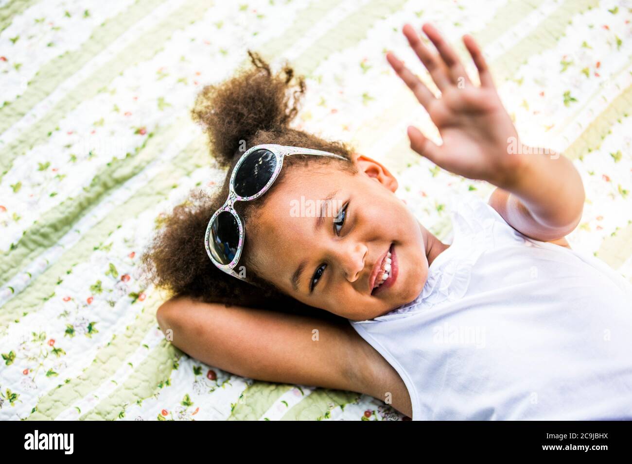 Fille couchée sur une couverture dans le parc, souriante, portrait. Banque D'Images