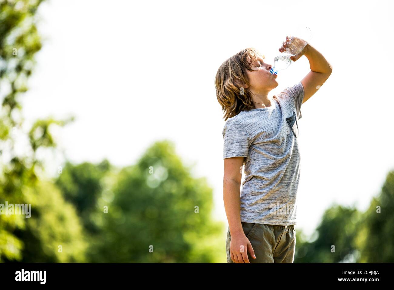 Garçon buvant de l'eau à partir d'une bouteille en plastique dans le parc. Banque D'Images