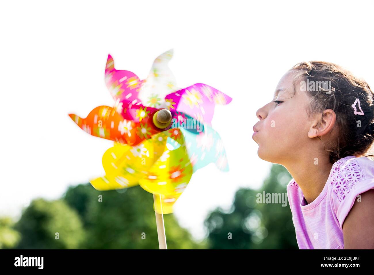 Jeune fille soufflant de papier multicolore moulin à vent, gros plan. Banque D'Images