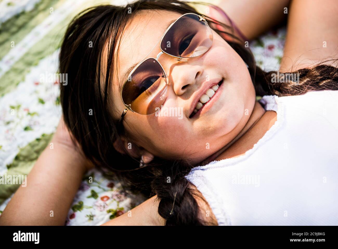 Fille couchée sur une couverture dans le parc, souriante, portrait. Banque D'Images