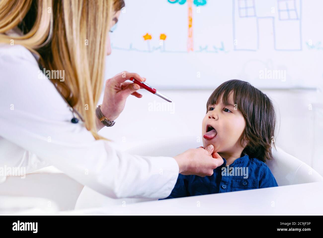 Pédiatre examinant la gorge d'un garçon à l'aide d'un stylo-torche. Banque D'Images