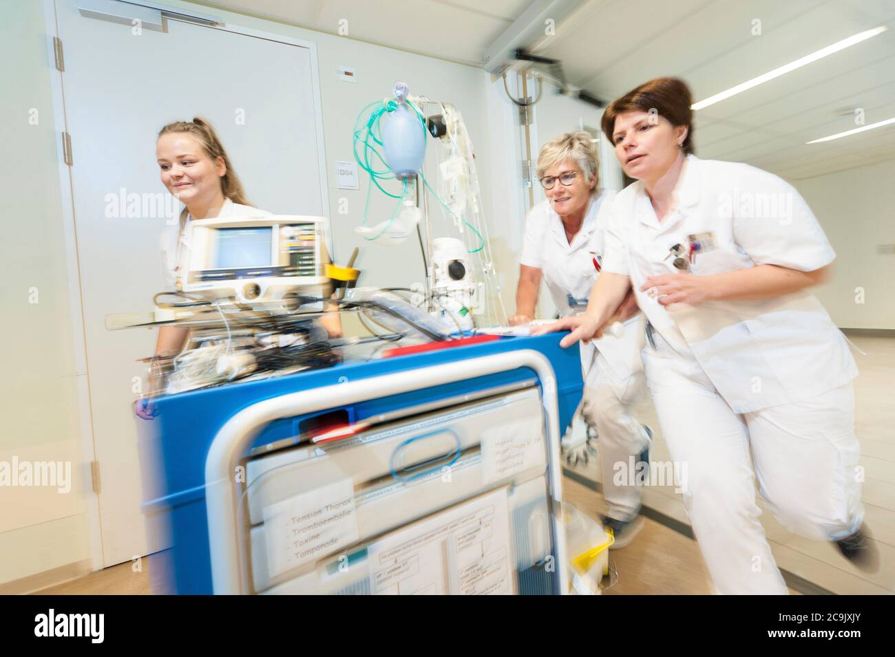 Service hospitalier gériatrique. Des infirmières qui passent dans le hall d'un service gériatrique de l'hôpital avec un chariot d'accident de traumatologie. Banque D'Images