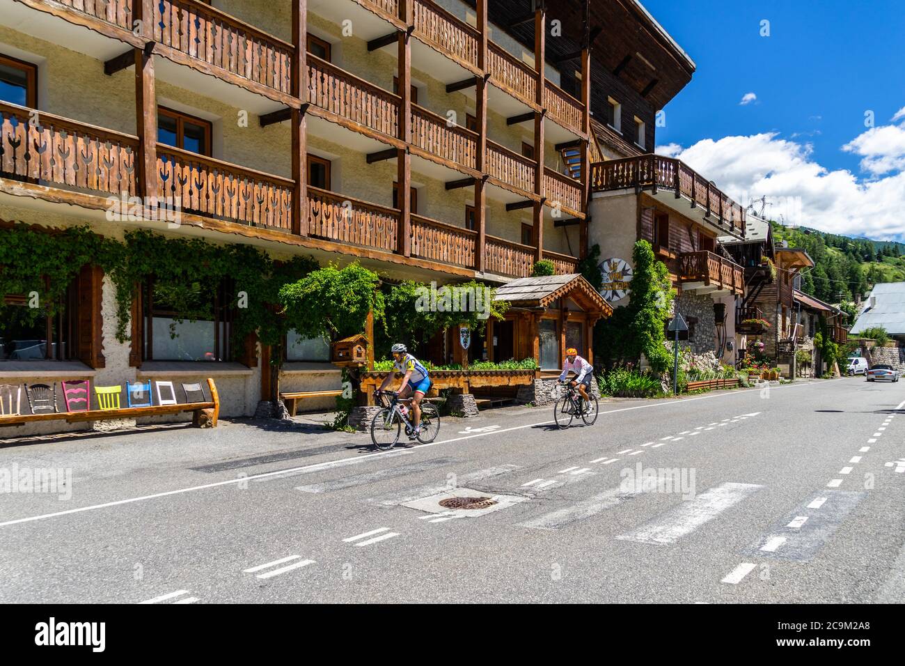 Cyclistes descendant du Col de Vars et passant par un village alpin avec des maisons en bois typiques. Vars, Hautes-Alpes, France, juillet 2020 Banque D'Images