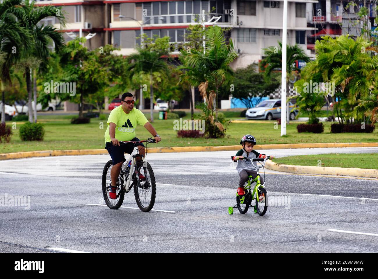 Adulte et enfant à vélo le long de l'Avenida Balboa dans la ville de Panama sur un dimanche circulation libre temps, Panama, Amérique centrale Banque D'Images