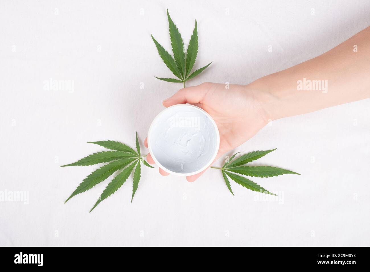 beauté, soins du corps cosmétiques avec extrait de marijuana. gommage du corps à la main avec des feuilles de plante de cannabis isolées sur fond blanc vue du dessus. Banque D'Images