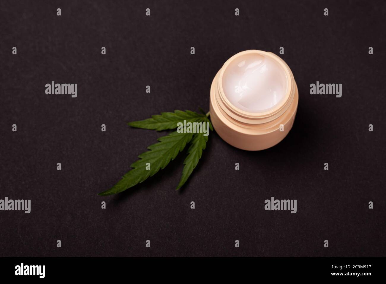 beauté, soins de la peau cosmétiques avec extrait de marijuana. crème pour les mains rajeunissante avec feuille de cannabis médical sur fond noir. Banque D'Images