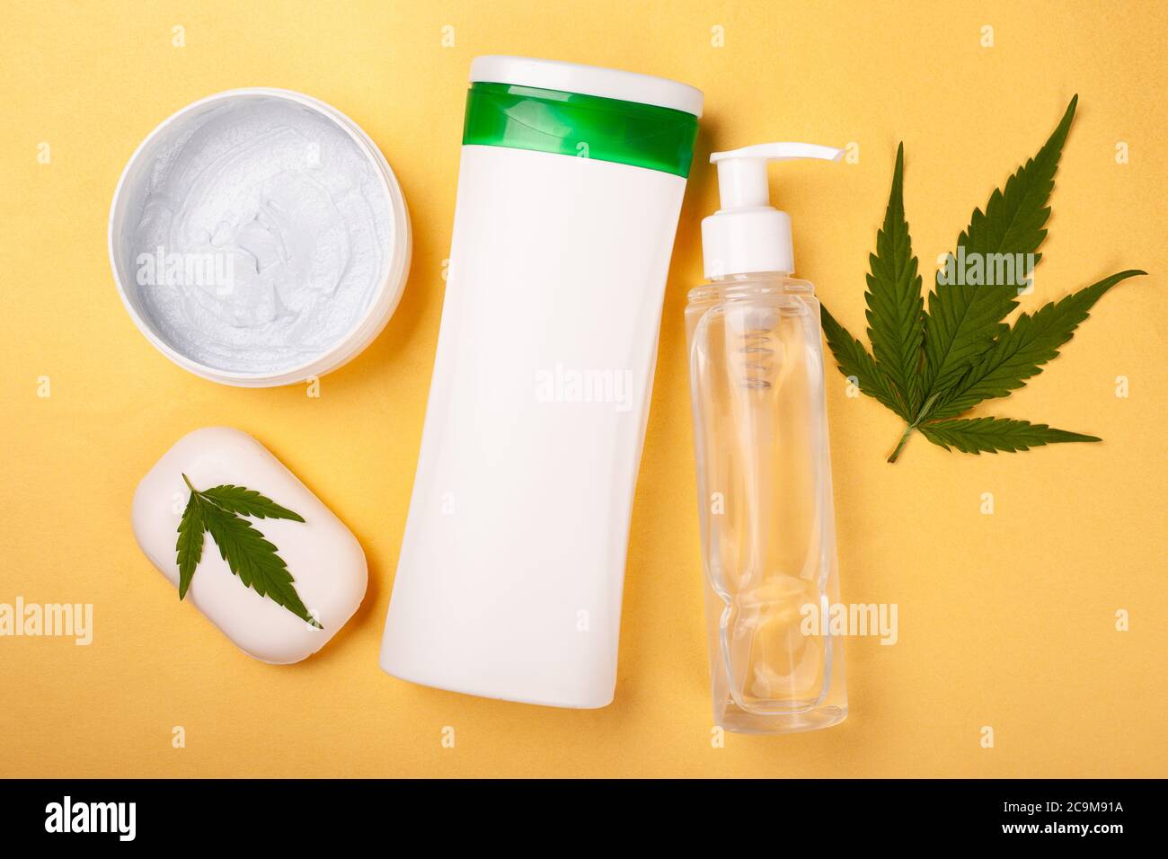 beauté, soins du corps cosmétiques avec extrait de marijuana sur fond jaune. bouteilles blanches avec cosmétiques et feuilles de cannabis. Banque D'Images