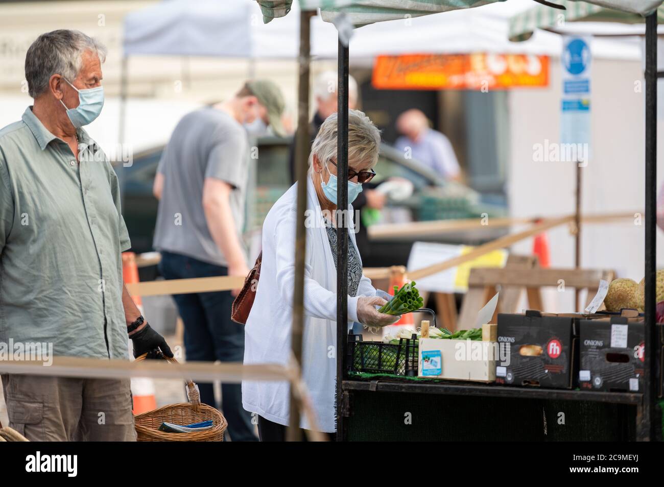 Richmond, North Yorkshire, Royaume-Uni - 1 août 2020 : une femme mature portant un masque facial protecteur faisant du shopping dans un marché aux fruits et légumes en plein air Banque D'Images