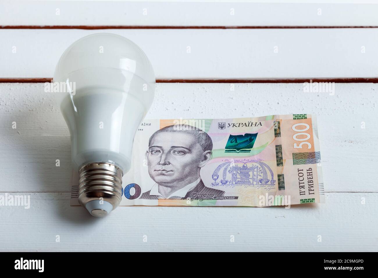 une ampoule led avec de l'argent se trouve sur une table en bois blanc du tableau. Banque D'Images