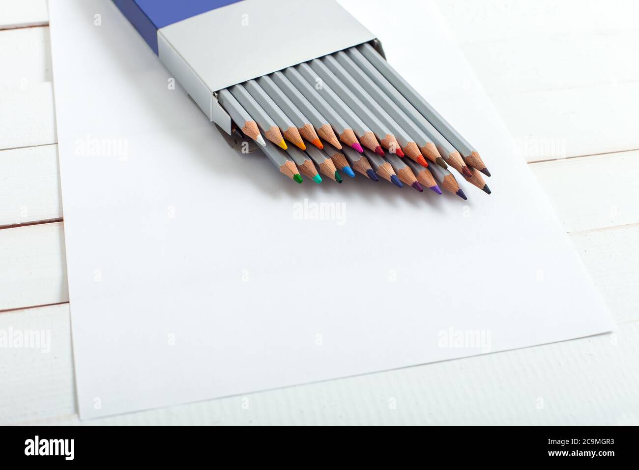 plusieurs crayons de couleur qui regardent d'un paquet qui sont sur la feuille de papier couché sur une table en bois de tableau blanc. Banque D'Images