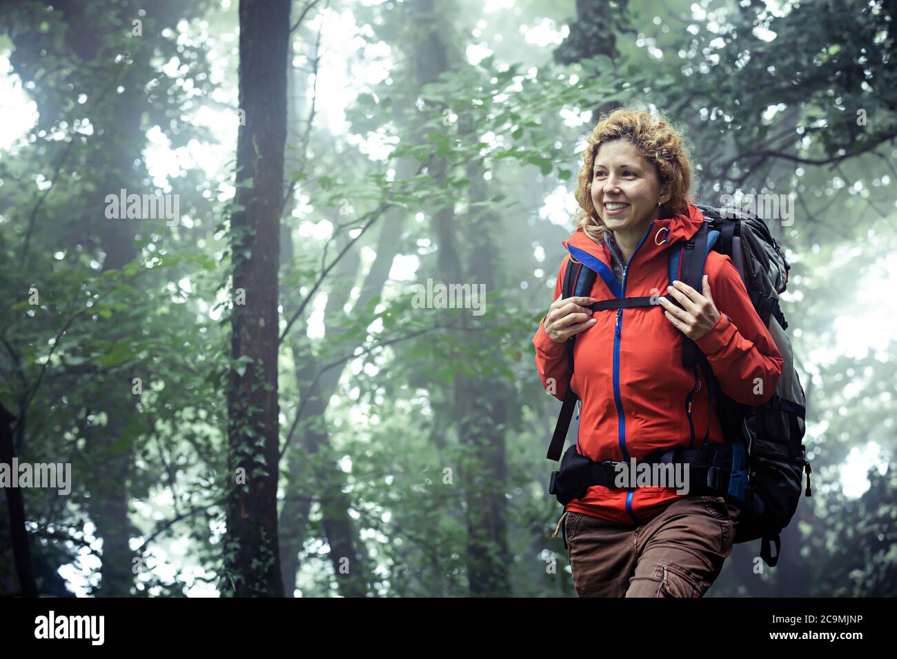 Souriante routard caucasien, marchant dans la forêt brumeuse. Banque D'Images