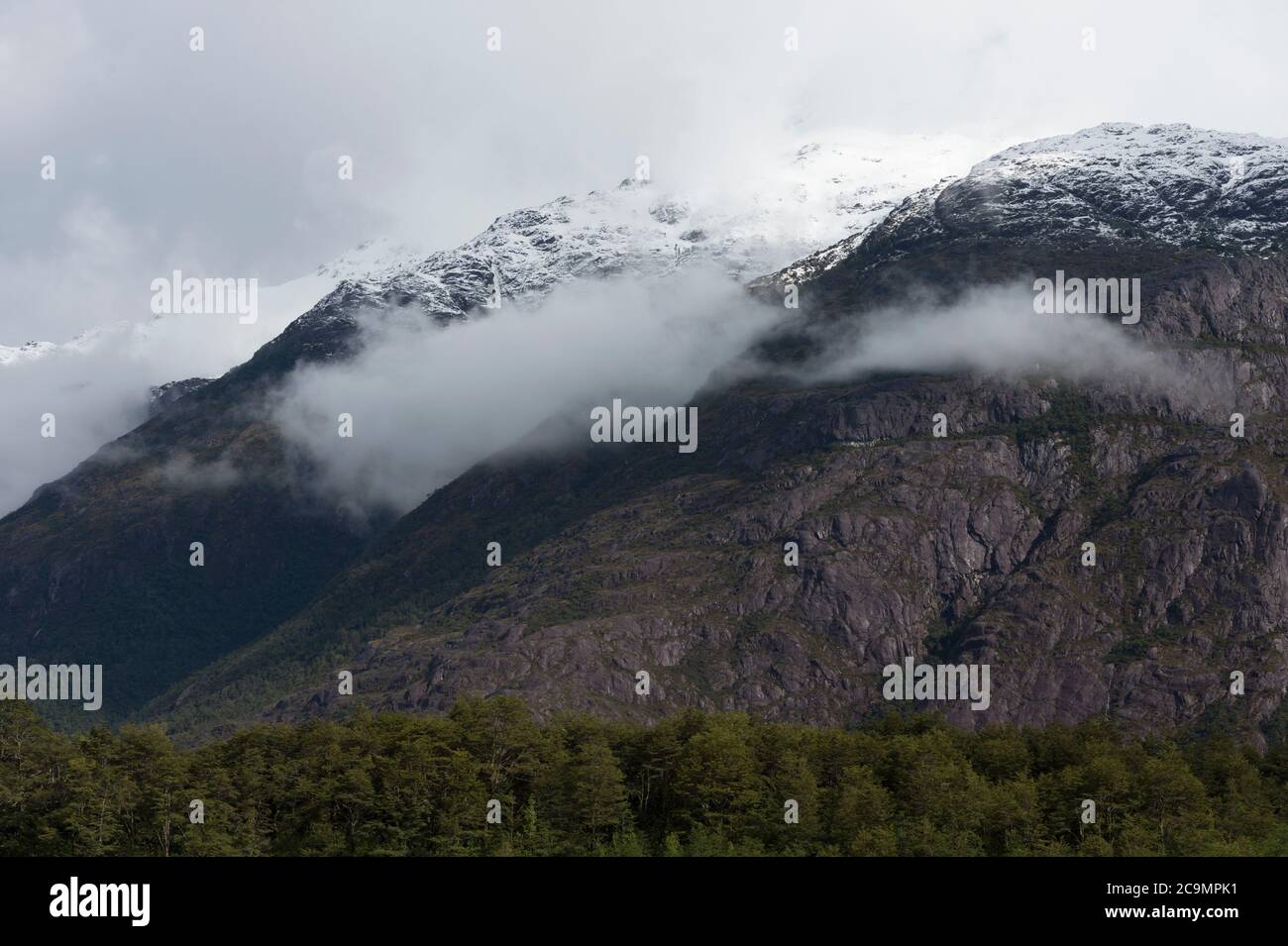 Sommets enneigés dans les nuages, Caleta Tortel, région d'Aysen, Patagonie, Chili Banque D'Images