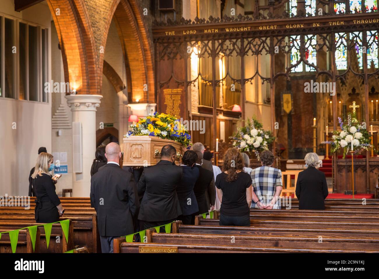Cercueil étant transporté dans une église à un enterrement socialement distancé Banque D'Images