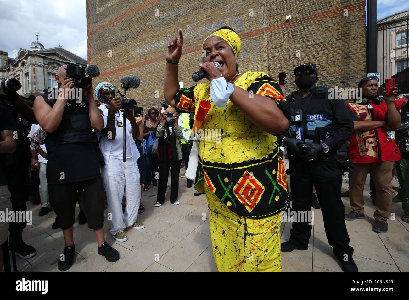 Une femme s'adresse aux manifestants qui soutiennent la campagne Halte à Maangamizi et le Comité de marche pour les réparations du jour de l'émancipation afrikan, avant de tenir un silence de trois minutes lors d'une manifestation sur la place Windrush à Brixton, Londres. Un couvre-feu et d'autres restrictions ont été imposés aux manifestations prévues dans le sud de Londres pour empêcher les personnes de bloquer les routes principales ou de planifier des événements musicaux illégaux, a déclaré Scotland Yard. Banque D'Images