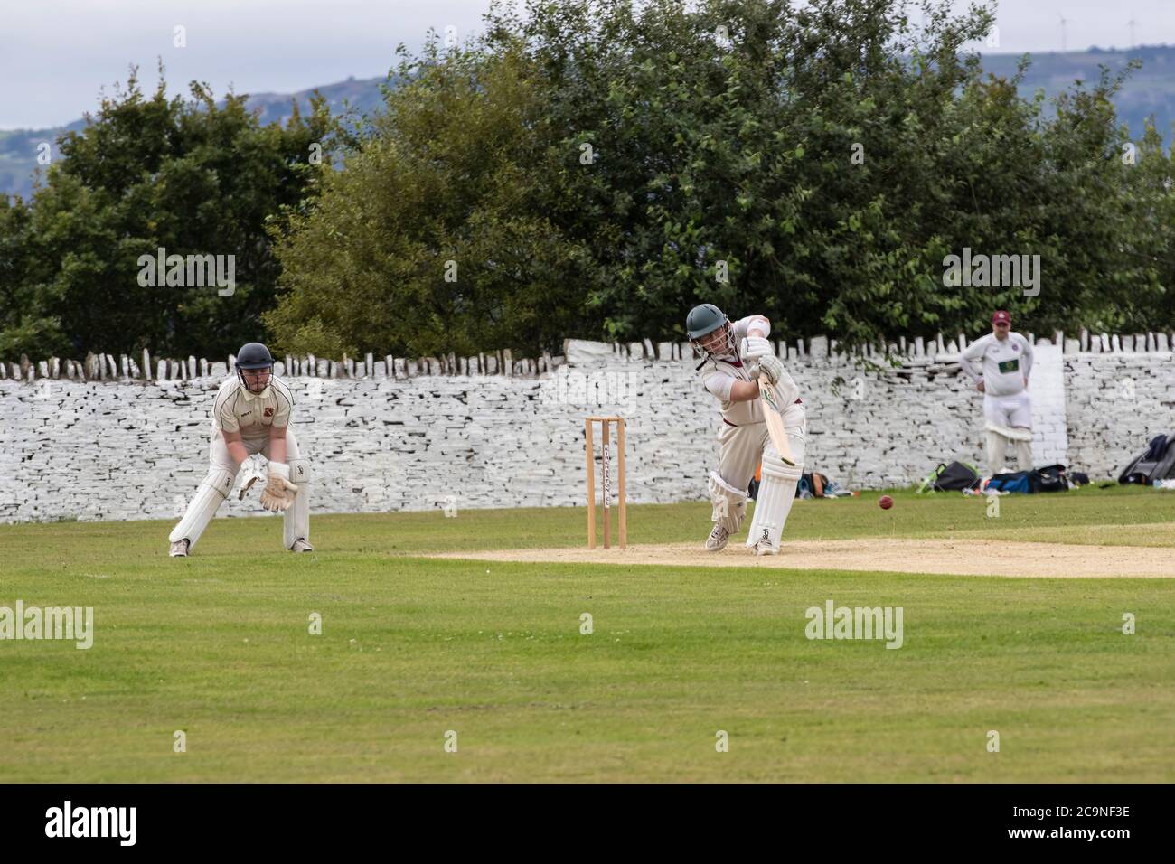 Batteur jouant un hors-route dans un match de cricket du village dans le West Yorkshire un samedi après-midi en août Banque D'Images