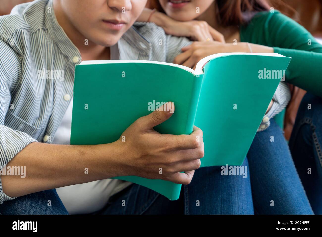 Un jeune couple asiatique lit le livre dans le salon. Banque D'Images