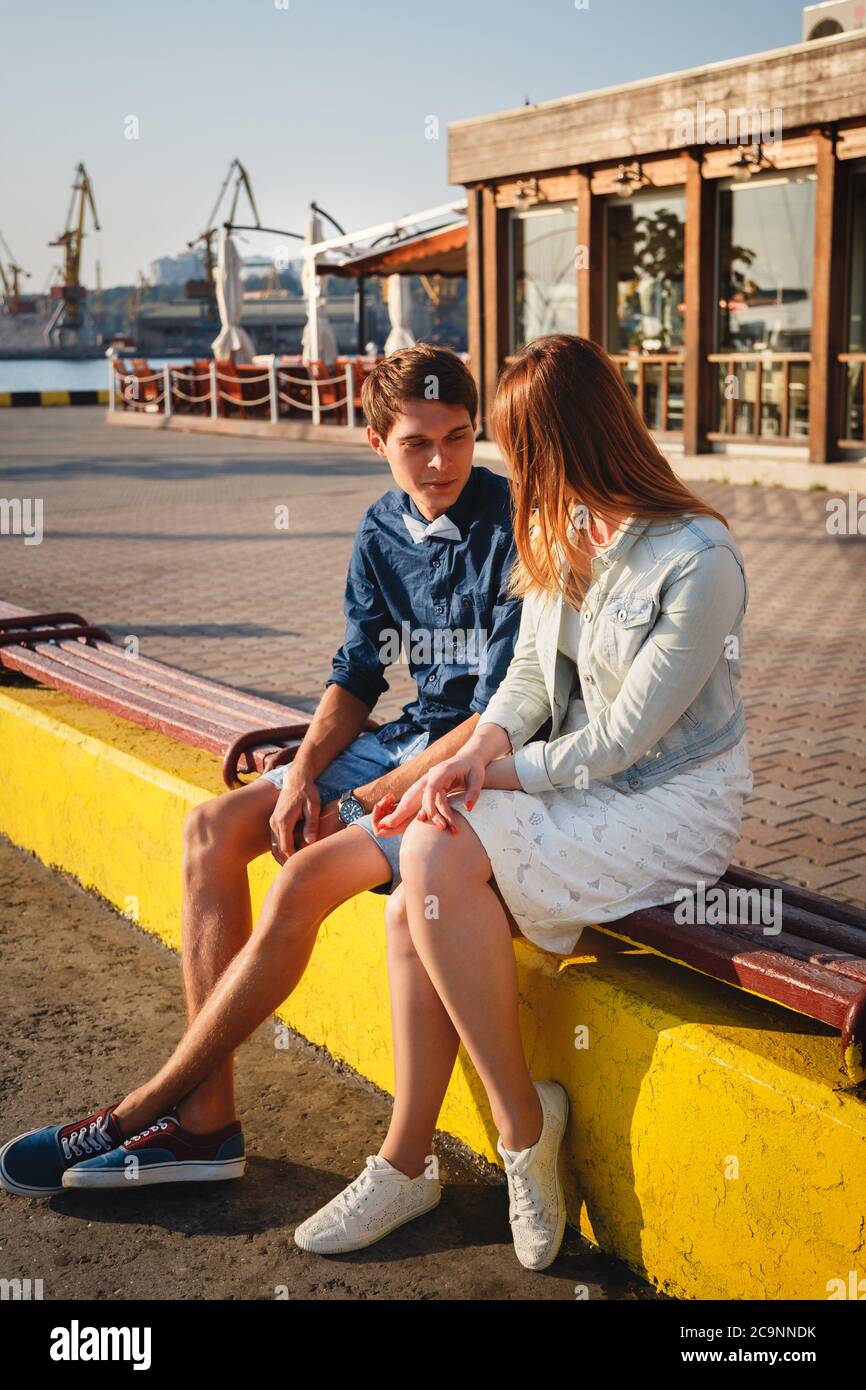Mignon jeune beau couple assis et s'embrassant ensemble à la jetée au port, des hipsters Banque D'Images