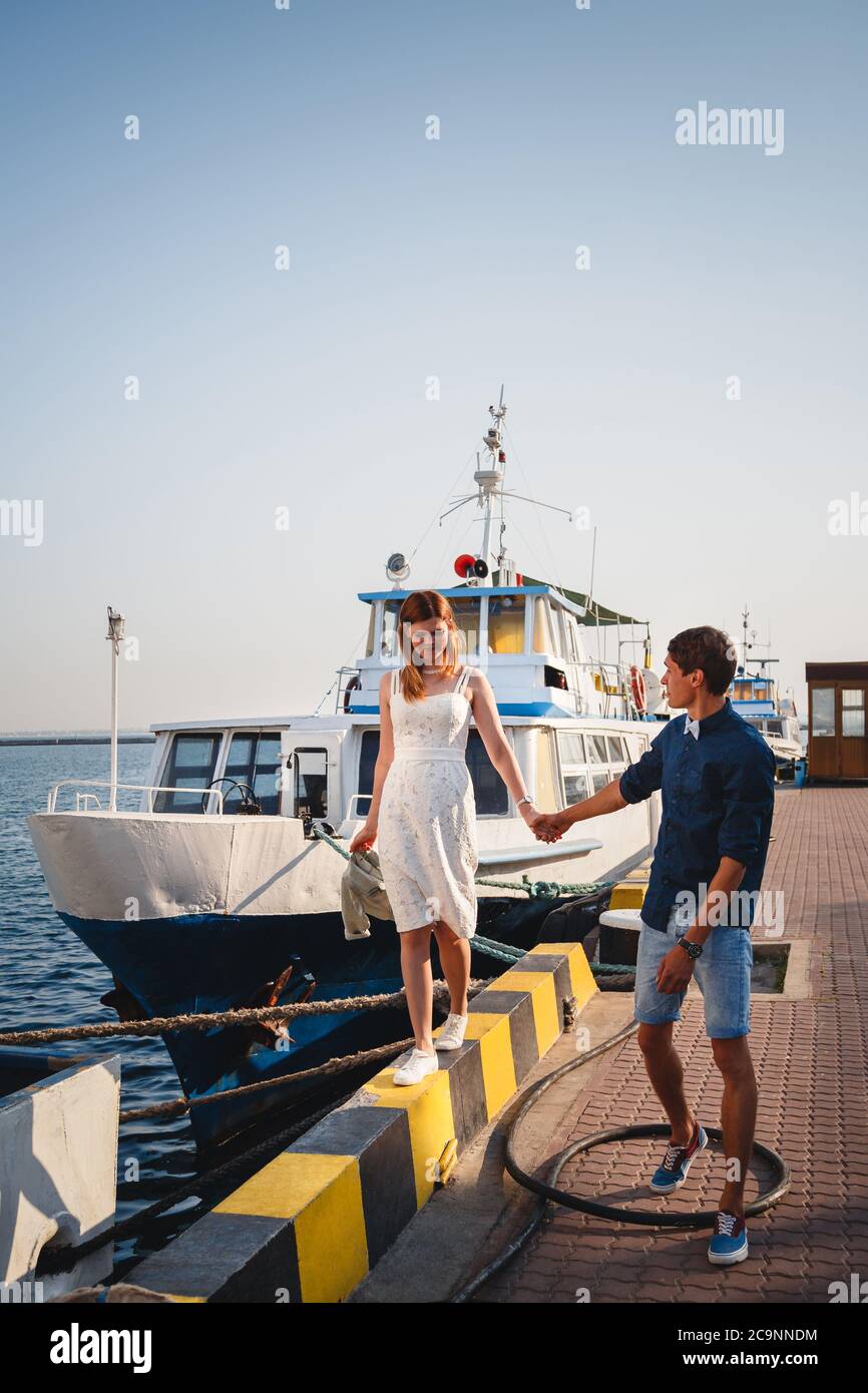 Mignon jeune beau couple à la jetée au port avec de petits yachts, hipster, heureux sourire portrait extérieur Banque D'Images