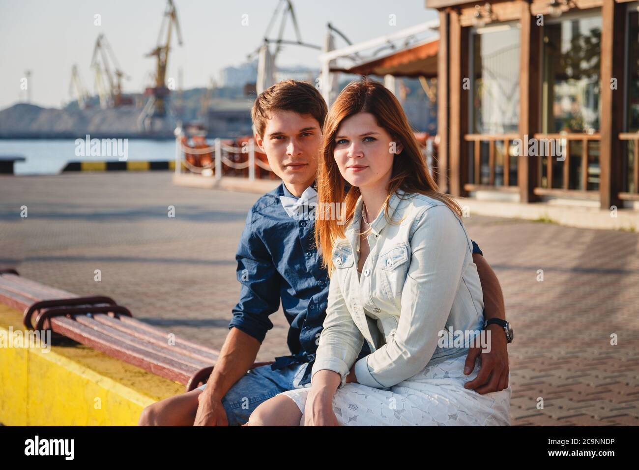 Mignon jeune beau couple assis et s'embrassant ensemble à la jetée au port, des hipsters Banque D'Images