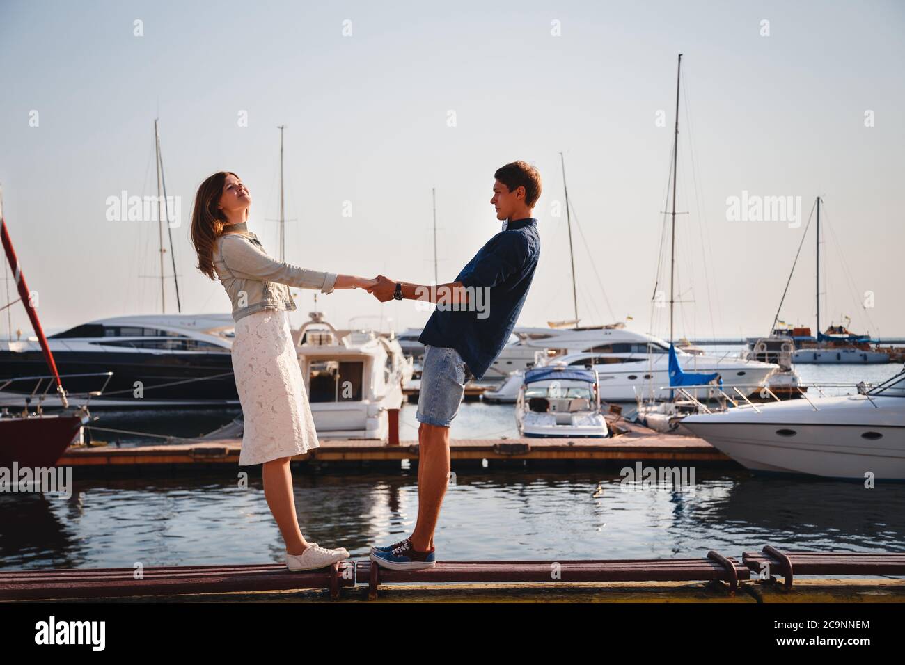 Mignon jeune beau couple à la jetée au port avec de petits yachts, hipster, heureux sourire portrait extérieur Banque D'Images