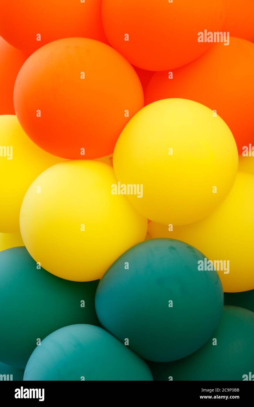 Gros plan d'un groupe de ballons de couleur verte, jaune et orange formant des rubans dans chaque couleur. Banque D'Images