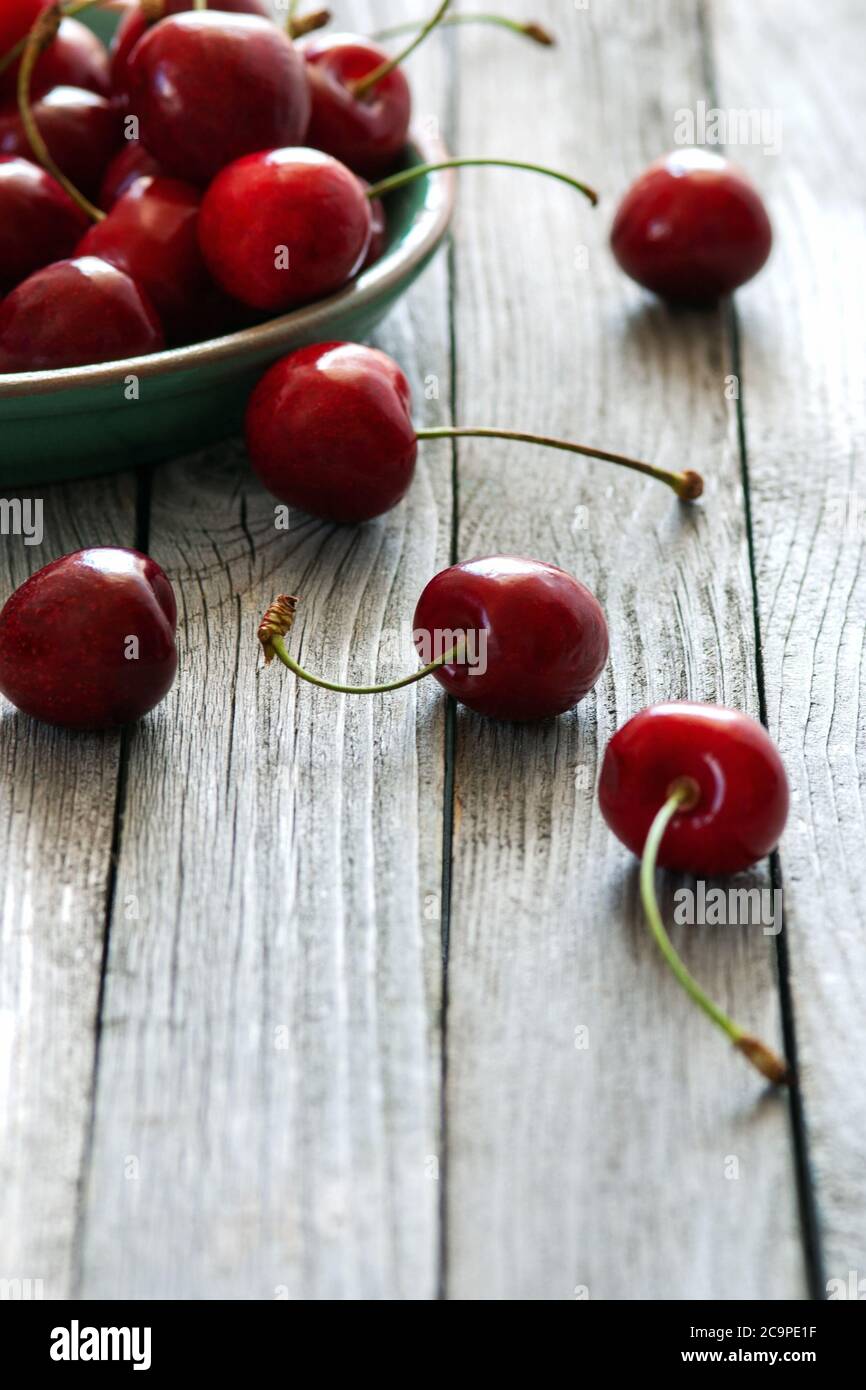 cerises rouges en plaque de céramique sur table en bois, grenaille verticale Banque D'Images